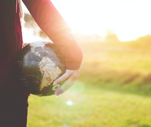 Man standing holding a black and brown round globe