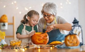 Grandma teaching her granddaughter how to prepare a pumpkin.